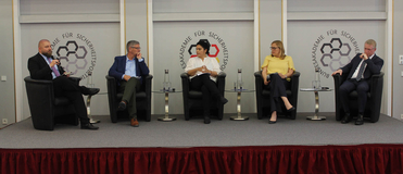 Eine Podiumsdiskussion mit fünf Teilnehmern (drei Männer, zwei Frauen) auf einer Bühne vor dem Logo der Bundesakademie für Sicherheitspolitik.